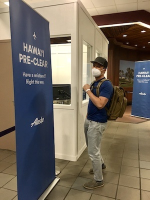 Jedd in HNL airport by sign for Hawaii pre-clearance program by Alaska Airlines