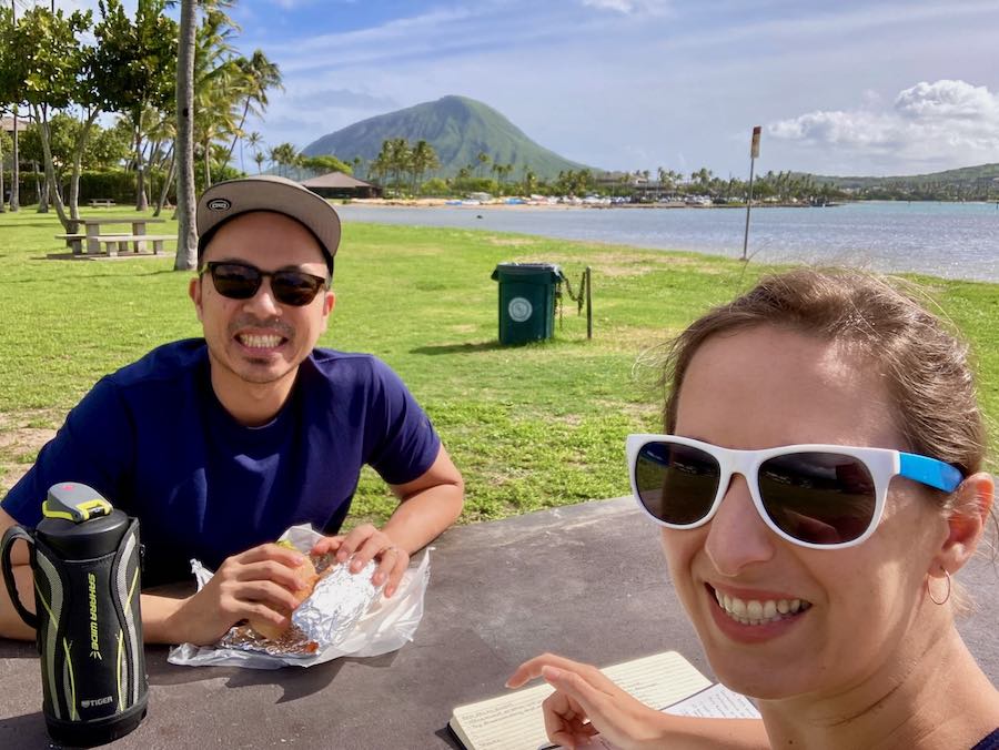 Jedd and Michelle in Hawaii Kai park eating a picnic with Koko Head and ocean in background
