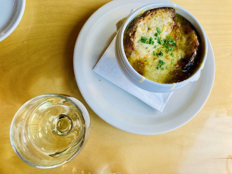overhead view of french onion soup and white wine glass