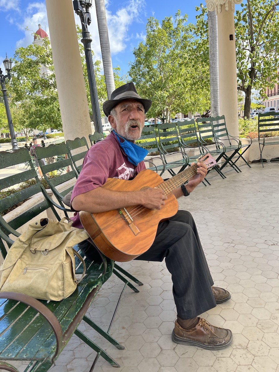 man playing guitar on park bench