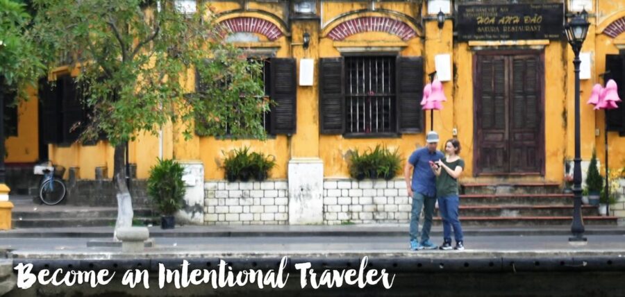 Become An Intentional Traveler - authors Jedd and Michelle looking at phone with Ancient Town in background