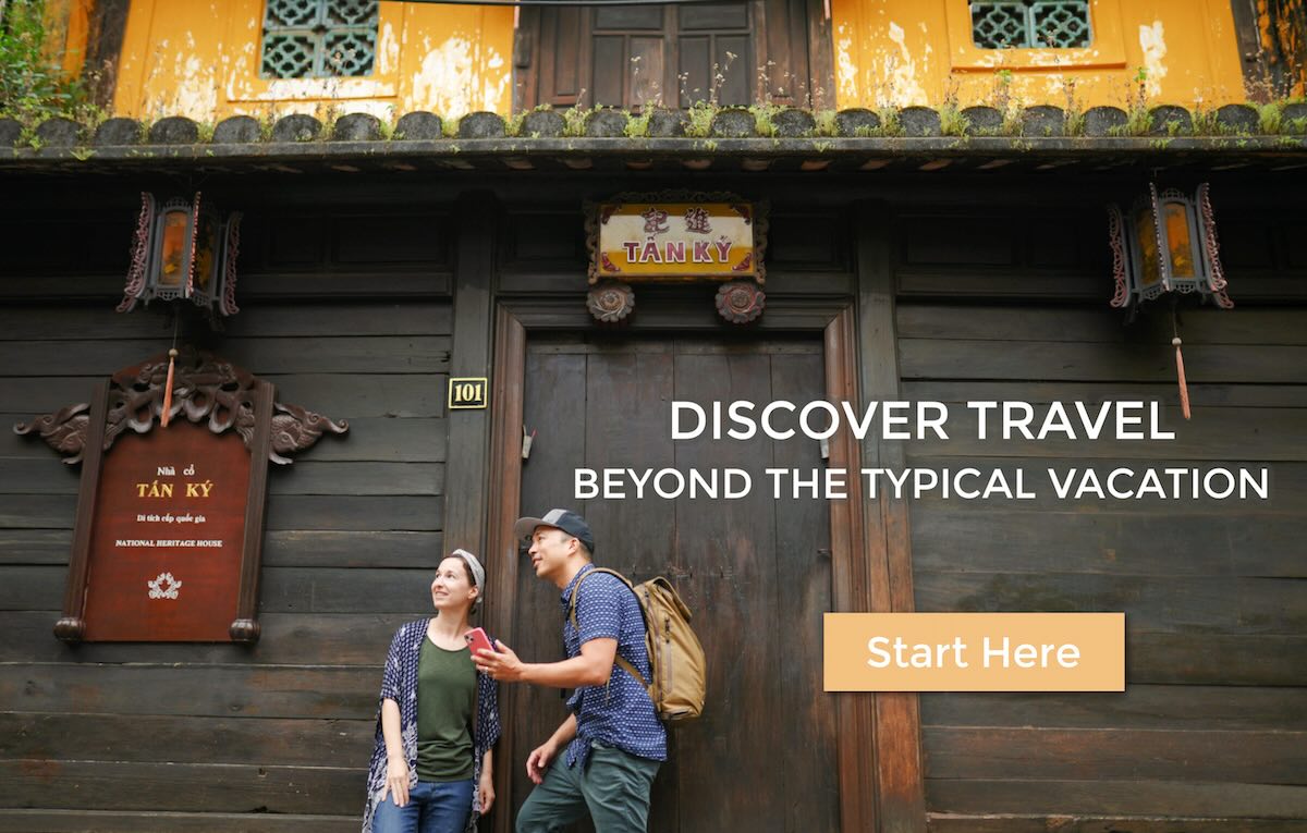 Intentional travelers Michelle and Jedd with backpack and smartphone exploring abroad in Vietnam in front of historic wood door - Discover Travel Beyond the Typical Vacation : Start Here