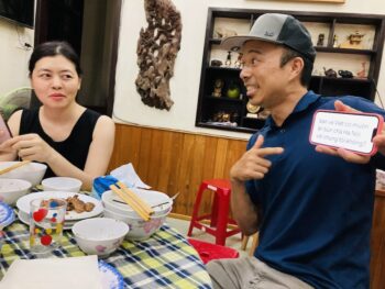 Jedd holding phone to show Google Translate message to Vietnamese family at dinner