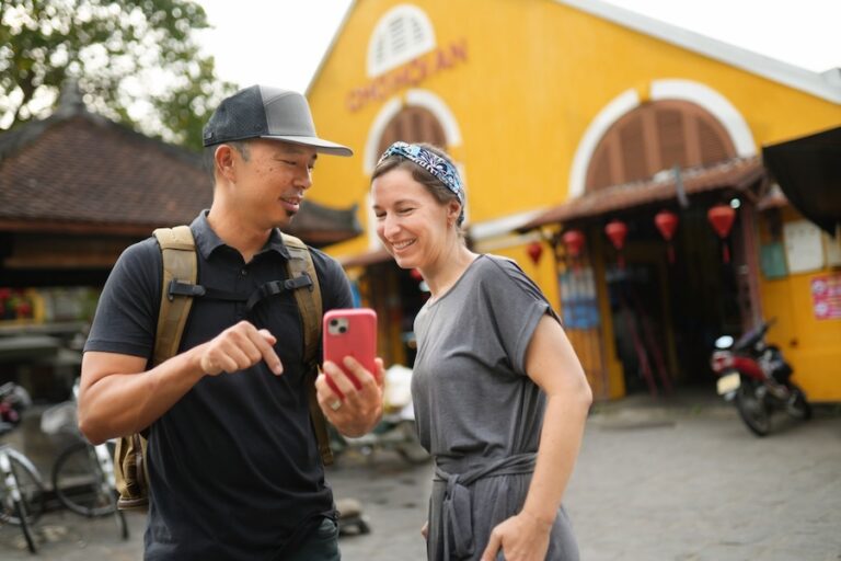 Jedd and Michelle looking at smartphone in front of Hoi An market