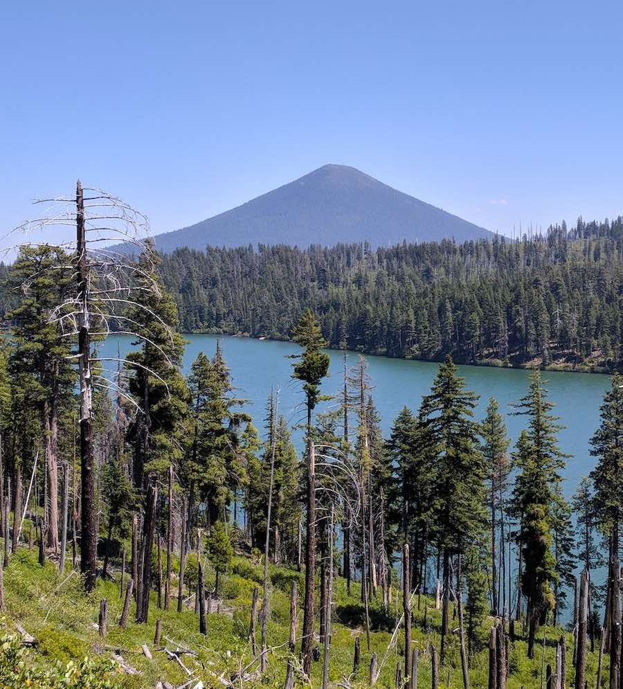 Scenic drive to Central Oregon with view of lake, forest, and volcano peak in the background.