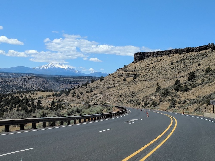 Road in Central Oregon with mountains and sky.