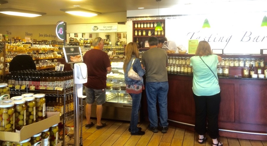 people in line at shop full of olive cans