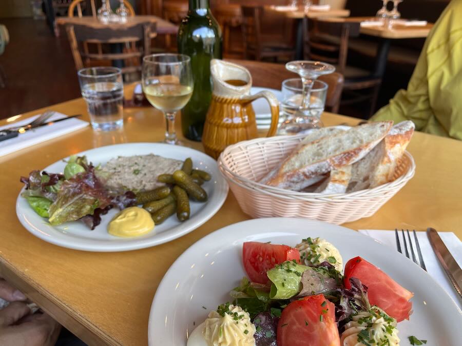 table with appetizer plates, bread bowl, white wine, and caraffe