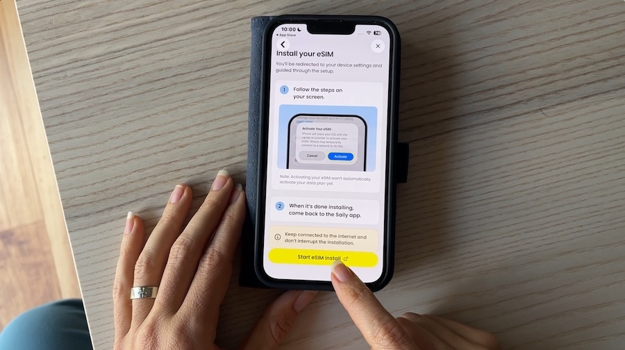 eSIM installation screen on smartphone with finger pointing to Install button